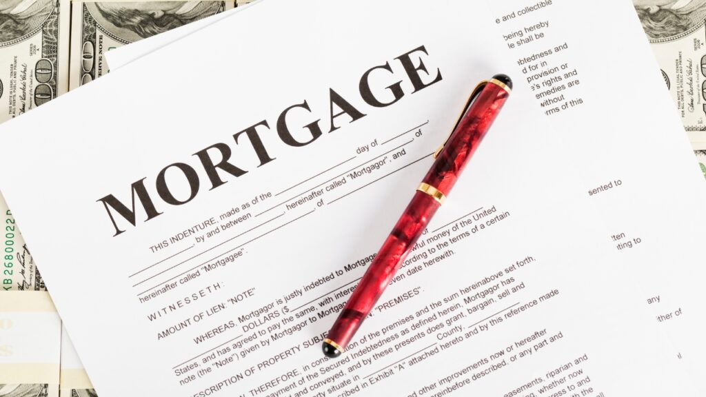 A mortgage document with bold text at the top, a red and gold pen resting on it.