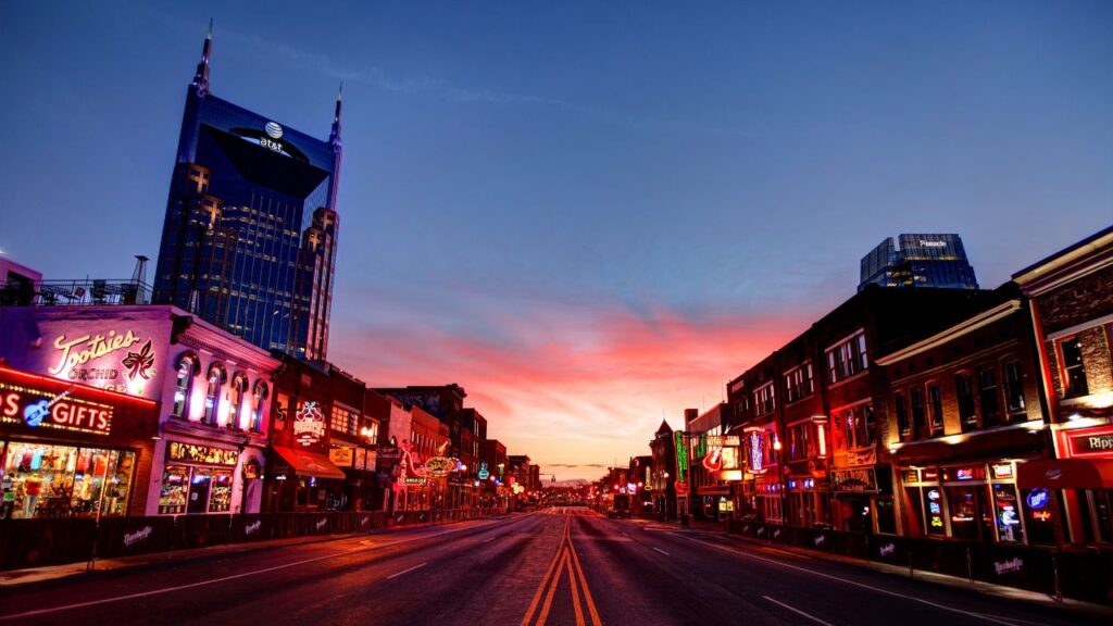 Neon-lit Broadway Street in Nashville at sunset.