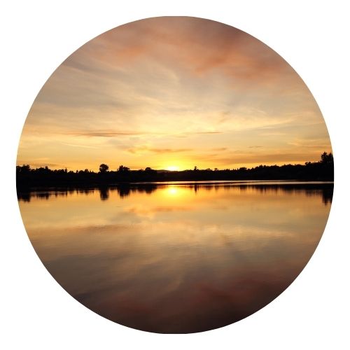 Calm lake at sunset reflecting colorful clouds.