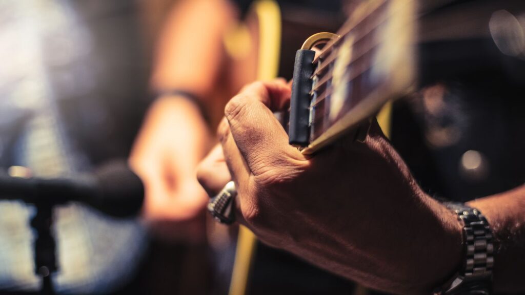 A close-up of a person playing an acoustic guitar near a microphone.