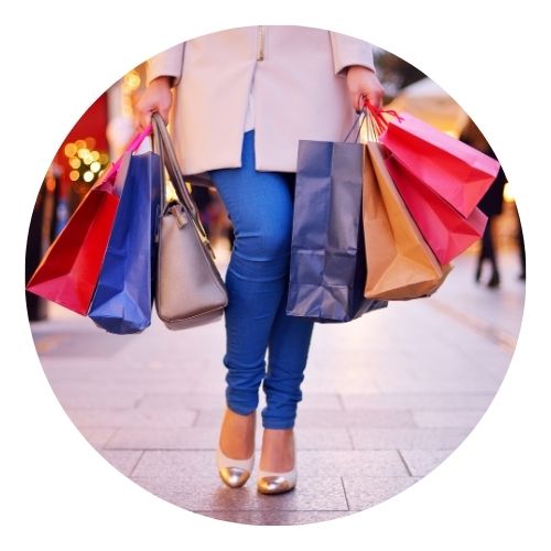 Person walking with arms full of colorful shopping bags.