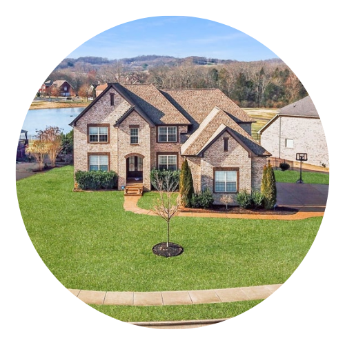 Large brick two-story house with a spacious front yard.
