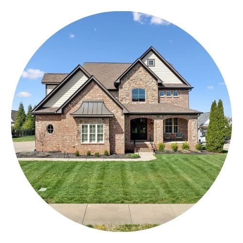 Brick house with gables and a manicured lawn under a blue sky.