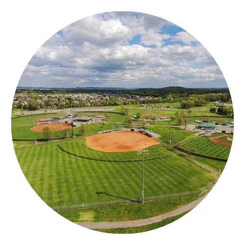 erial view of multiple baseball fields in a large green park.