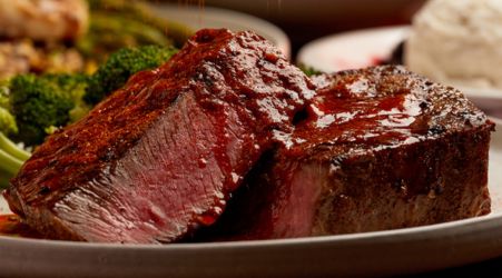 A sliced, medium-rare filet mignon served with broccoli and mashed potatoes.