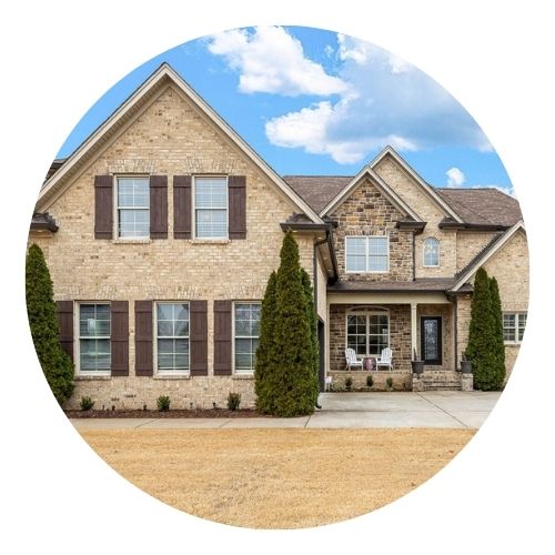 Two-story brick and stone home with tall windows, a covered entryway, and manicured landscaping.