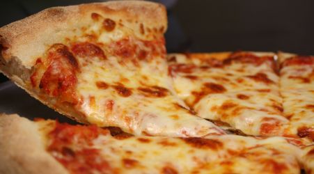 Slice of cheesy pepperoni pizza being lifted from the pie.