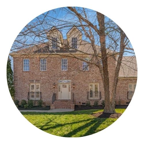 Traditional brick home with symmetrical windows, a central front door, and bare trees in the front yard.