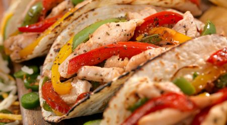 Chicken fajita tacos filled with grilled peppers and onions.