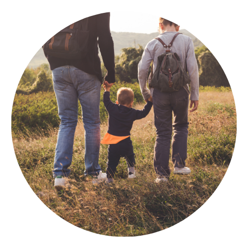 Parents walking with a young child through a field.