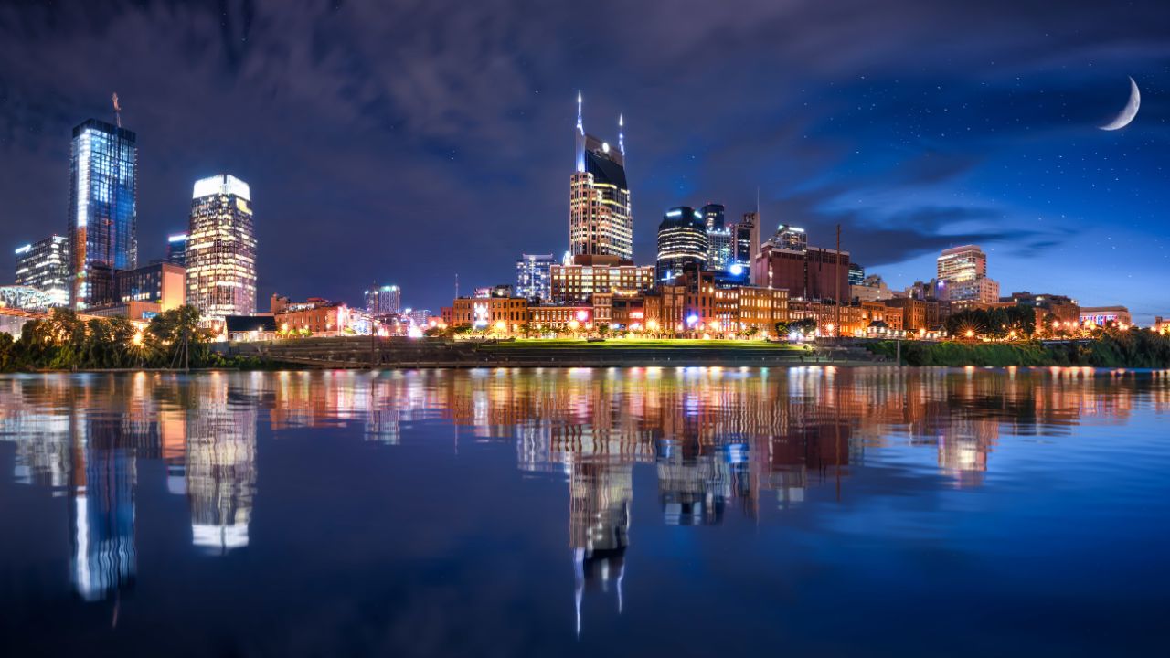 Nashville city skyline at night reflecting on the water.
