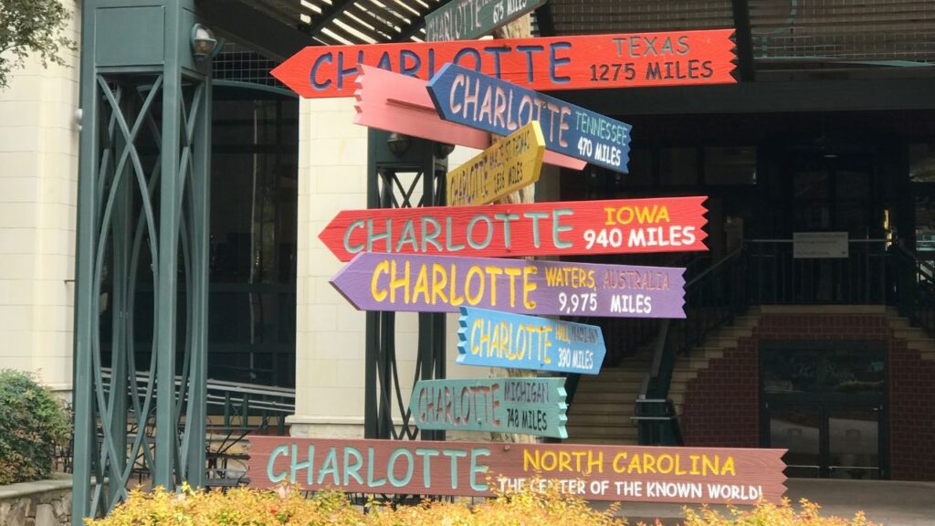 Colorful directional signs pointing to different places named Charlotte.