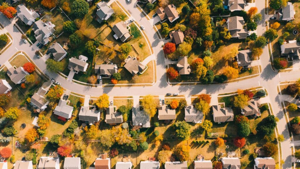 Aerial view of a suburban neighborhood with houses and colorful trees.