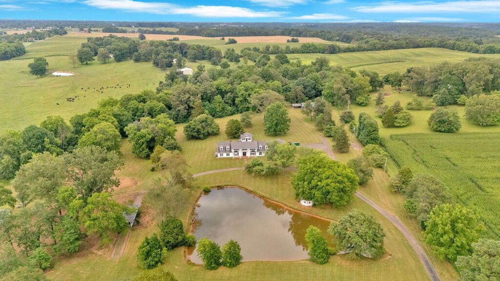 Aerial view of a farmhouse with pond and surrounding farmland in Portland, Tennessee.