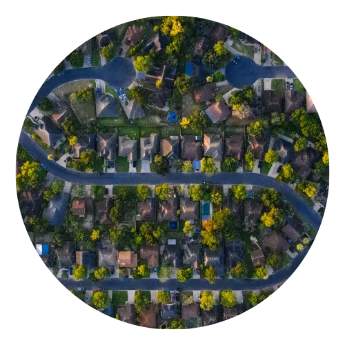 Aerial view of a tree-lined residential neighborhood with winding streets and varied rooftops.