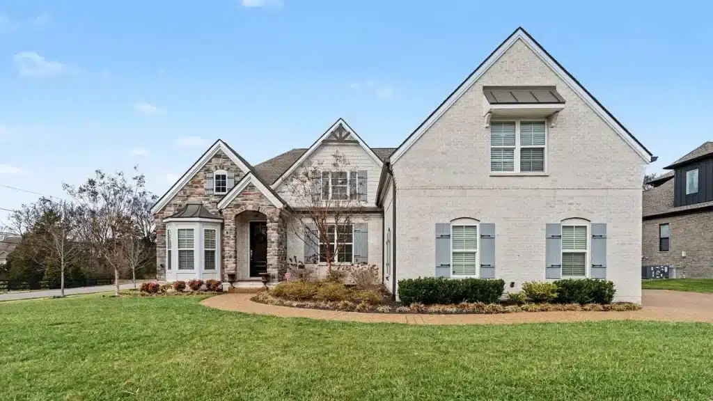 A two-story brick and stone home in Hendersonville with gray shutters, a circular driveway, and a manicured front lawn.