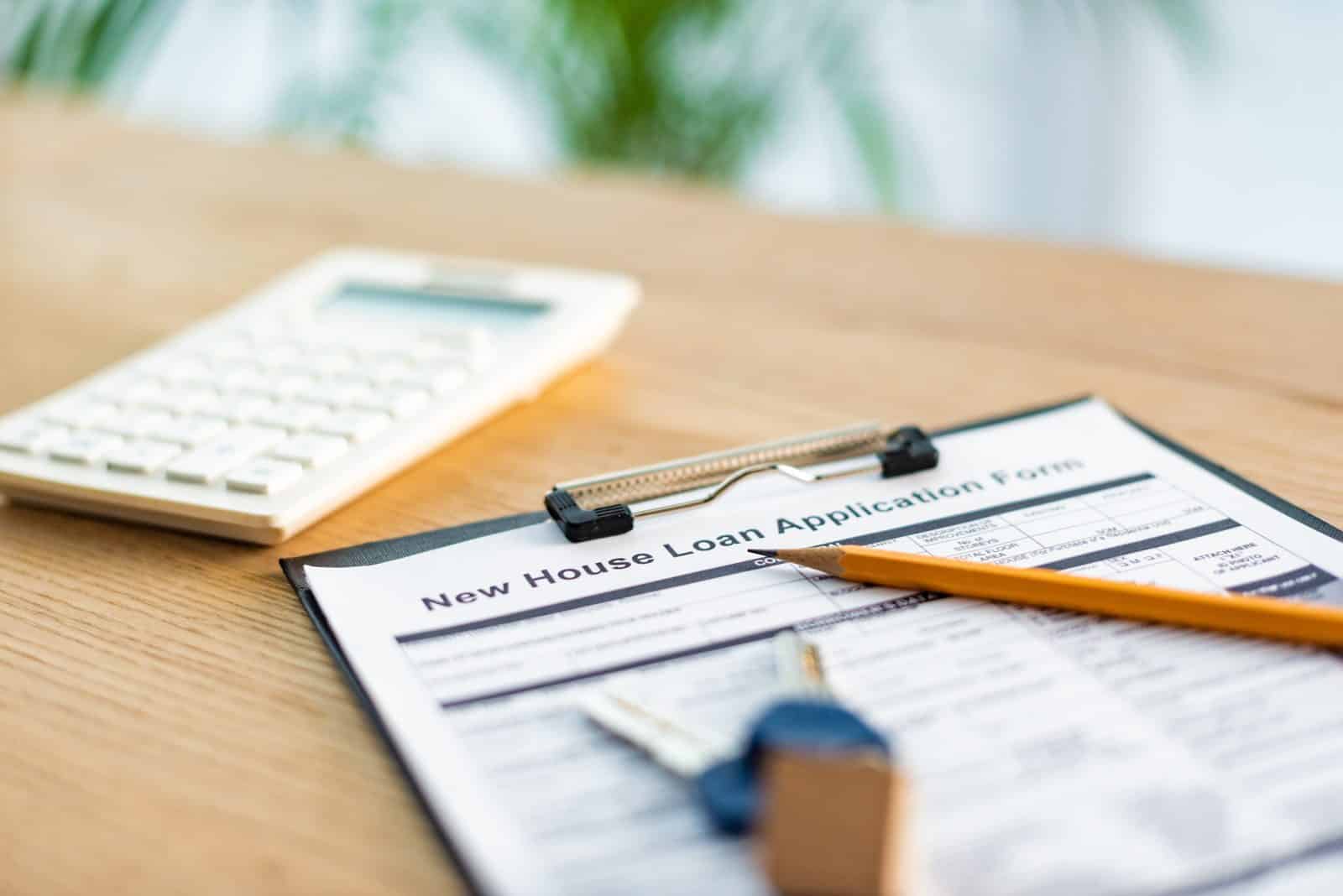 Home loan application form on a desk with house keys and a calculator