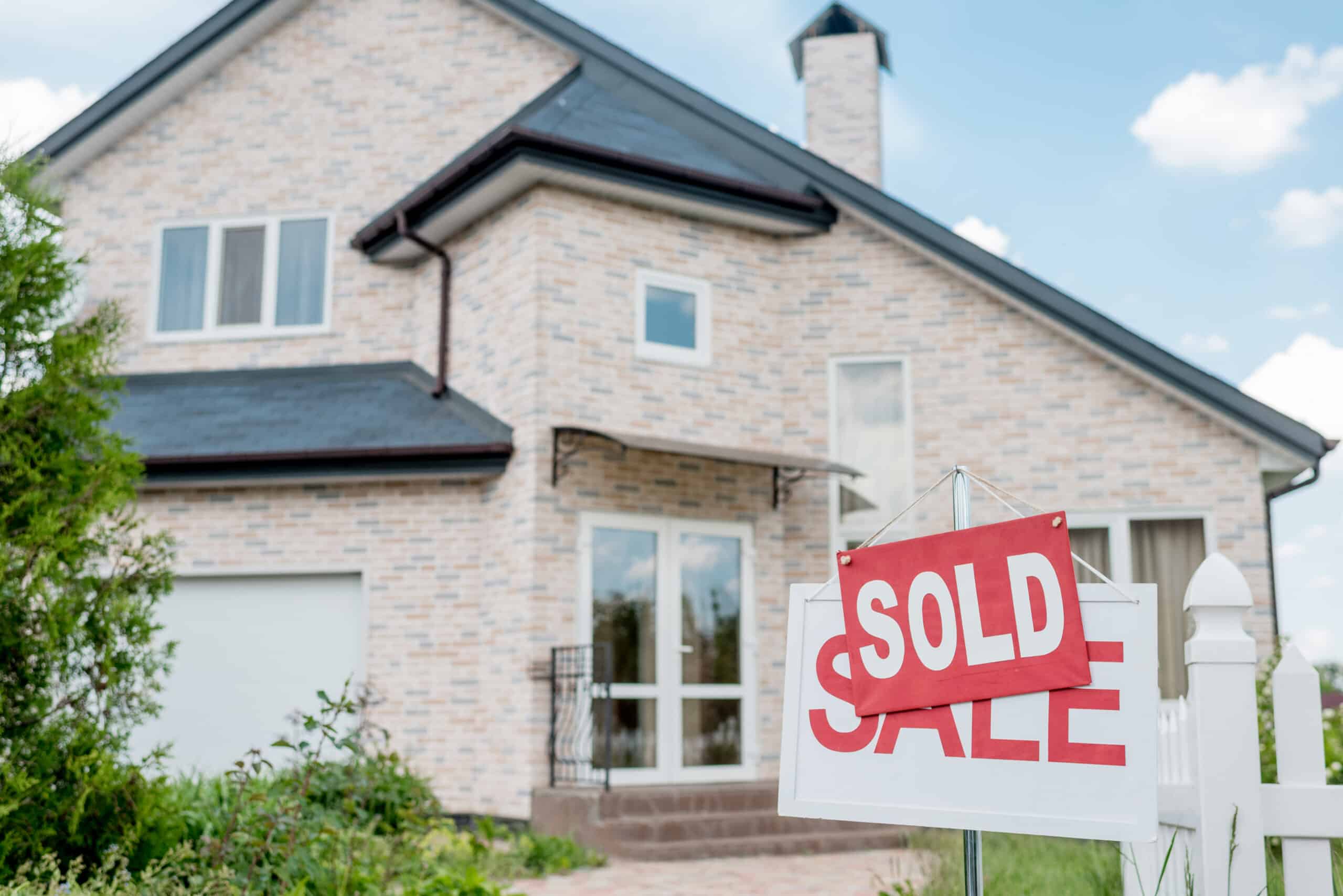 Sold sign in front of a brick house
